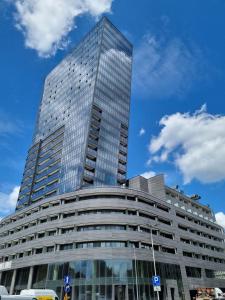 un edificio alto de cristal con un cielo azul en JBHotels Apartament Comfort Hanza Tower, en Szczecin