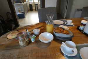 einen Holztisch mit Brot und Kaffee sowie eine Flasche Orangensaft in der Unterkunft Le Héron bleu de la Brenne in Tournon-Saint-Martin
