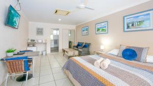 a bedroom with two beds and a desk and a room at Yamba Twin Pines Motel in Yamba