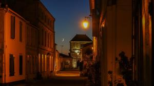 an alley at night with a building in the background at La Martinoise Patio in Saint-Martin-de-Ré