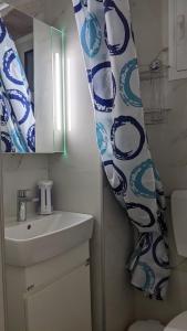 a bathroom with a sink and a blue and white shower curtain at Emanuela SunnySide in Kavála