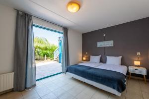 ein Schlafzimmer mit einem Bett und einem großen Fenster in der Unterkunft Grimaud 185 - Kustpark Village Scaldia in Hoofdplaat