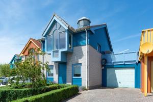 una casa azul y blanca con garaje en Grimaud 185 - Kustpark Village Scaldia, en Hoofdplaat