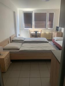 ein Schlafzimmer mit einem Bett, einem Tisch und zwei Fenstern in der Unterkunft Apartmány Havlíčkova in Mladá Boleslav