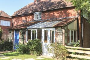 een oud bakstenen huis met een witte deur bij Godshill Park Cottages in Godshill