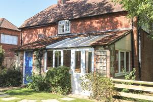 an old brick house with a white door at Godshill Park Cottages in Godshill