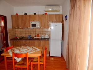 a kitchen with a table and a white refrigerator at Adrienn Apartments in Stari Grad