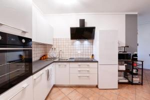 a kitchen with white cabinets and black appliances at Wolf House - Peschiera Holiday - Jacuzzi Privata in Peschiera del Garda