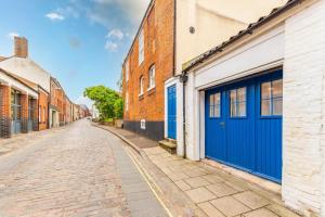 an empty street with blue doors and brick buildings at The Artists Workshop - Norfolk Holiday Properties in Norwich