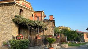 une maison en pierre avec une clôture et des fleurs dans l'établissement Antico Casale da Gemma, à Fuscaldo