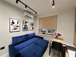 Dolce far niente Apartment في تيرانا: غرفة معيشة مع أريكة زرقاء وطاولة