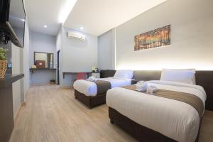 a hotel room with two beds and a television at Tarnsiri Boutique Resort in Kanchanaburi City