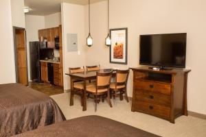 a room with a dining room table with a flat screen tv at Teddy's Residential Suites Watford City in Watford City
