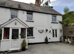 a white house with a white door and windows at Rooms by the River at Glan Aber in Cynwyd