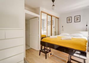 ein Schlafzimmer mit einem Bett mit einer gelben Decke in der Unterkunft L'HYPERCENTRE de Suresnes in Suresnes