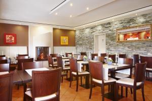 a restaurant with tables and chairs and a stone wall at Landhotel Lembergblick in Feilbingert