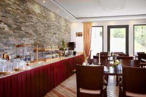 a restaurant with a long bar with tables and chairs at Landhotel Lembergblick in Feilbingert