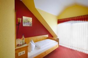 Bett in einem Zimmer mit roter Wand in der Unterkunft Landhotel Lembergblick in Feilbingert