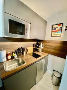 a kitchen with a sink and a microwave at Superbe Studio Balcon Emplacement nº1: Place Morny in Deauville