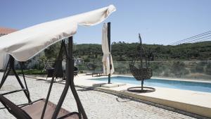 ein Stuhl und ein Sonnenschirm neben einem Pool in der Unterkunft Casas do Aidro in Freches