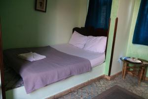 uma pequena cama com lençóis e almofadas roxos num quarto em Alf Leila Boutique Hotel em Dahab