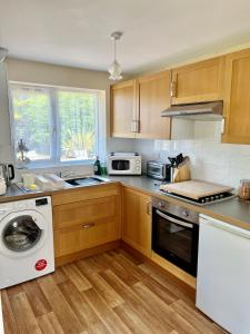 a kitchen with wooden cabinets and a washer and dryer at New Forest Hideaway- Self Catering Accommodation in Newbridge