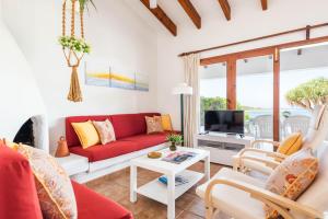un soggiorno con divano rosso e TV di Bellamirada - Punta Prima Playa a Punta Prima