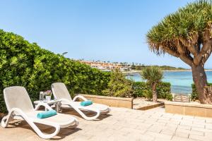 2 sillones sentados en un patio cerca del océano en Bellamirada - Punta Prima Playa, en Punta Prima