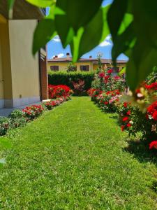 een tuin met rode en roze bloemen en een gebouw bij Casa Andrè in Pescantina