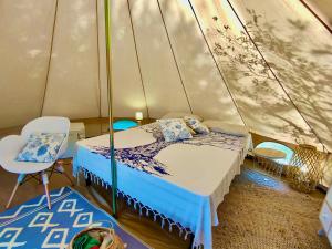 a bedroom with a bed and a chair in a tent at La Tenda a Marina Serra di Casa Camilla Journey in Marina Serra