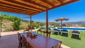 a wooden table and chairs on a patio with a pool at Casa El Mirador de Isabel Vélez-Málaga by Ruralidays in Vélez-Málaga