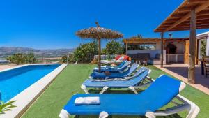 a group of blue lounge chairs next to a swimming pool at Casa El Mirador de Isabel Vélez-Málaga by Ruralidays in Vélez-Málaga