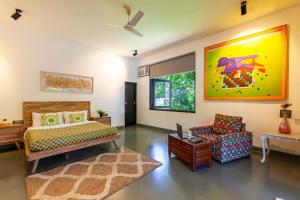 a bedroom with a bed and a chair in it at StayVista at El Parque with Pvt Pool & Indoor-Outdoor Games in Alibaug +27 photos