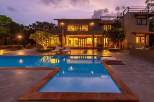 uma casa com piscina em frente a uma casa em StayVista at El Parque em Alibaug