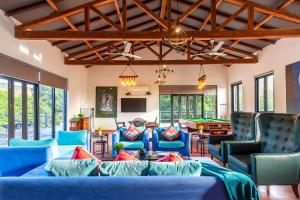 uma sala de estar com sofás azuis e uma mesa de bilhar em StayVista at El Parque em Alibaug