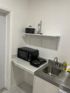 una cucina con forno a microonde su un bancone accanto a un lavandino di Sandelwood Studios' a Nassau