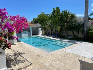 a swimming pool in the backyard of a house with purple flowers at Sandelwood Studios' in Nassau