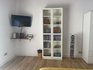 a living room with a white book shelf with books at Habitación agregada, Suite frente a la piscina 2 P habitación no casa completa in San Vicente del Raspeig