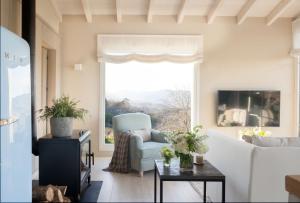 a living room with a couch and a chair and a window at La Guarida Lugás cabañas de lujo in Villaviciosa