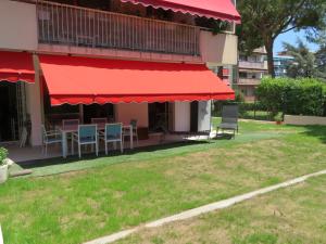 un patio avec des tables et des chaises et un auvent rouge dans l'établissement Superbe Rez de Jardin dans résidence au calme, à Nice