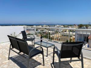a patio with three chairs and a glass table on a balcony at Noufaro rooftop-sea view apartment in Zipárion