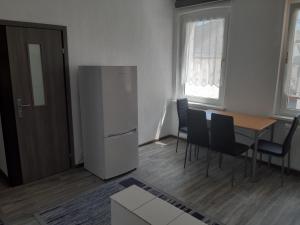 Il comprend une cuisine équipée d'un réfrigérateur, d'une table et de chaises. dans l'établissement 2 Zimmer Wohnung für 4 Personen, à Gößnitz