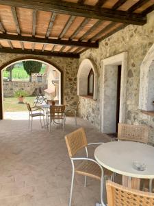 un patio con mesas y sillas y una pared de piedra. en Podere le Mulina, en Castiglione dʼOrcia