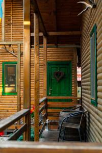 eine grüne Tür auf einem Holzhaus mit einem Tisch und Stühlen in der Unterkunft Fanni Kulcsosházak in Zetea