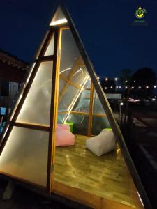 a glass house with pillows on a deck at night at Glamping Alas Duren Yogyakarta in Beran-kidul
