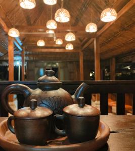 dois potes de chá sentados num prato sobre uma mesa em Glamping Alas Duren Yogyakarta em Beran-kidul