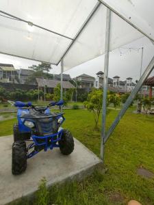 un ATV blu parcheggiato sotto una tenda in un campo. di Glamping Alas Duren Yogyakarta a Beran-kidul