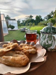 Beran-kidulにあるGlamping Alas Duren Yogyakartaのお茶と一緒にテーブルの上に並ぶペストリー