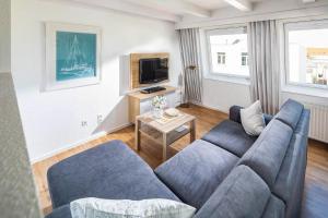 sala de estar con sofá azul y TV en Haus 3 Jahreszeiten Wg 16 en Norderney
