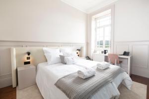 a white bedroom with a large white bed with towels on it at Casa Noronha Lima - Historic Stay in Alvarenga